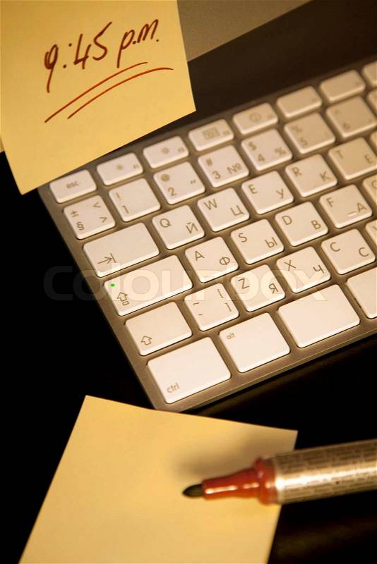 Post-it note with a reminder sticked on a computer screen with keyboard and a marker, stock photo