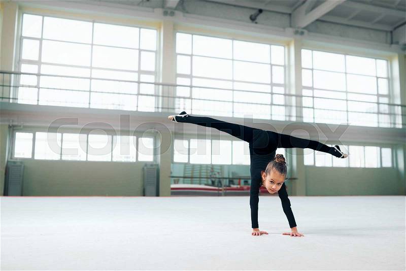 Little gymnast standing on hand doing the splits, stock photo