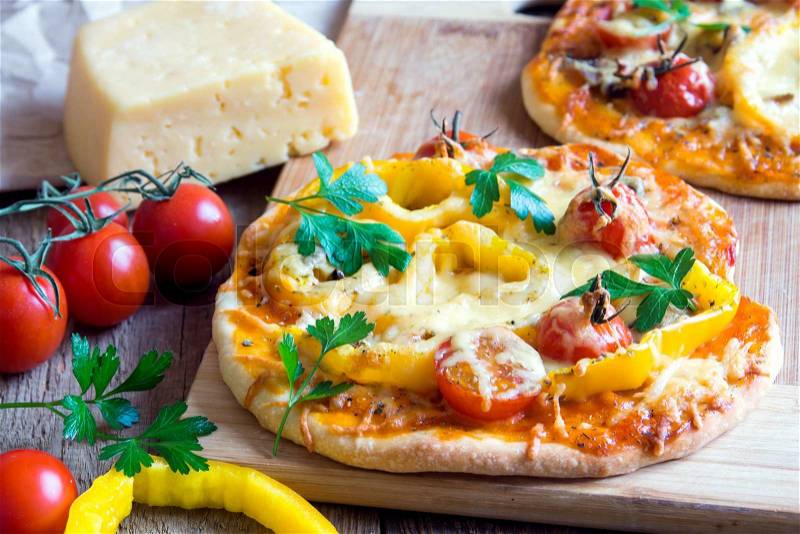 Vegetable pizza and ingredients on wooden cuting board, stock photo