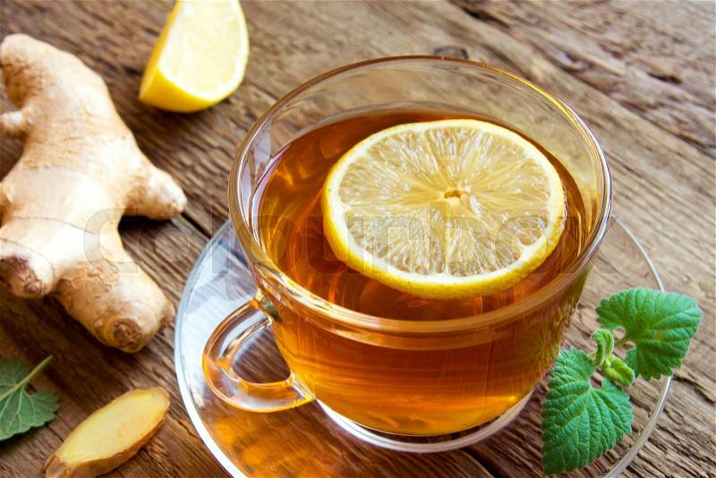 Tea with lemon, ginger, honey and mint leaves in cup over rustic wooden background, stock photo