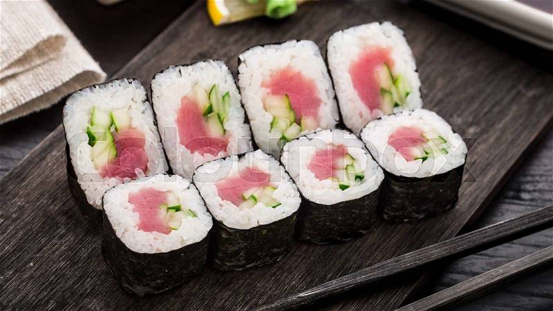 Sushi rolls with tuna and cucumber on a wooden board, stock photo