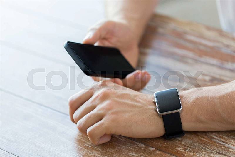 Business, technology and people concept - close up of male hand holding smart phone and wearing watch at home, stock photo