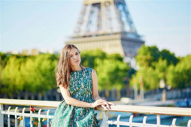 Beautiful young Parisian woman near the Eiffel tower on a summer day, stock photo