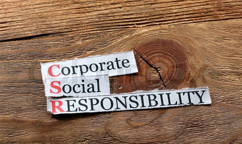 Corporate social responsibility (CSR) concept on paper on wood, stock photo