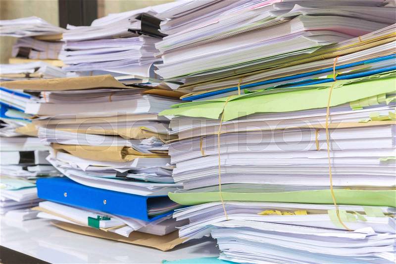 Pile of documents on desk stack up high waiting to be managed, stock photo