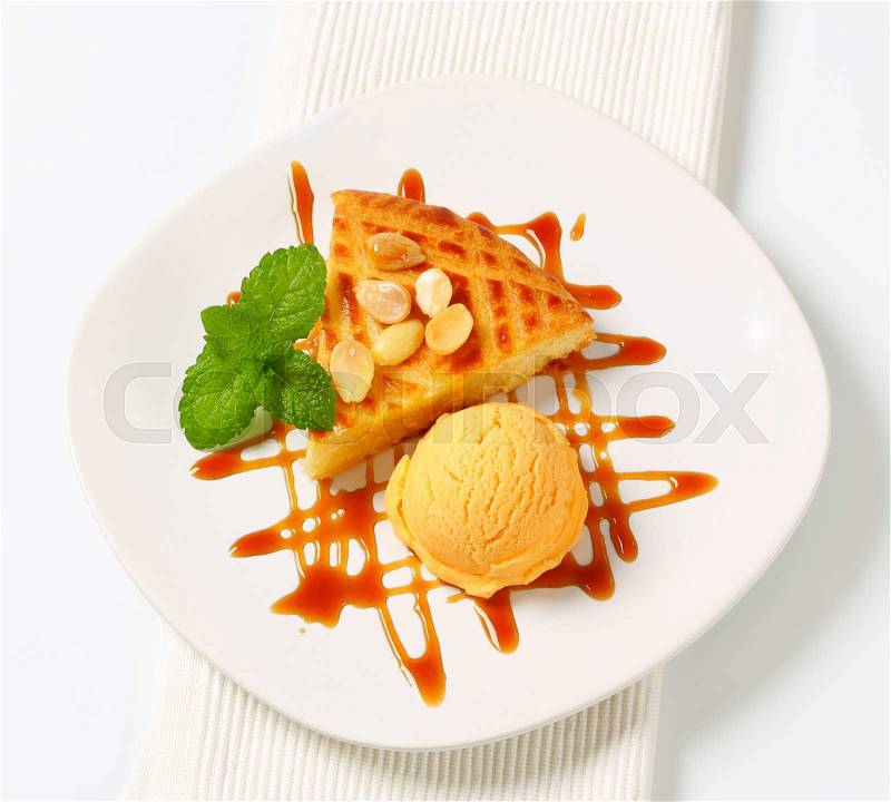 Almond cake with scoop of ice cream and caramel sauce, stock photo