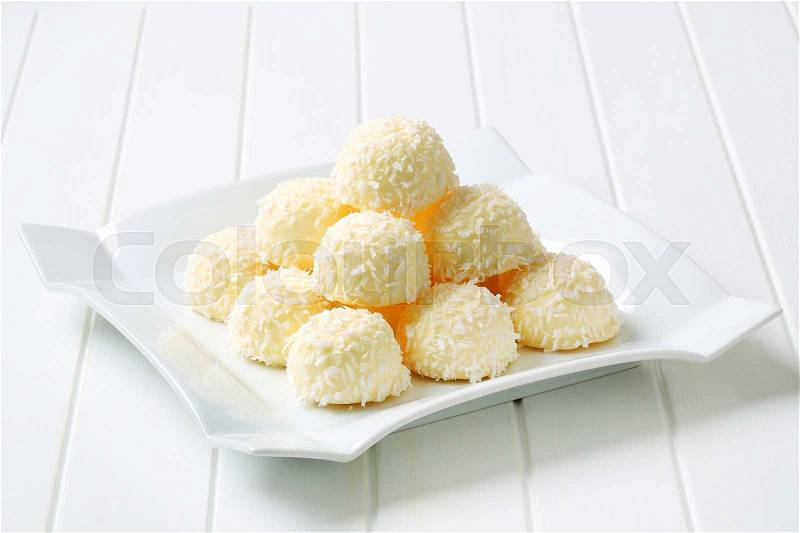 Pile of coconut snowball truffles on square plate, stock photo