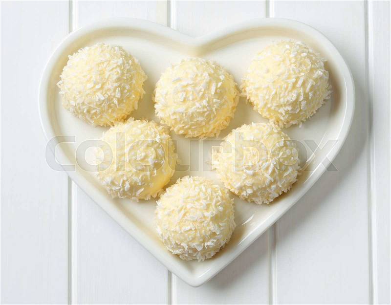 Coconut snowball truffles on heart-shaped plate, stock photo