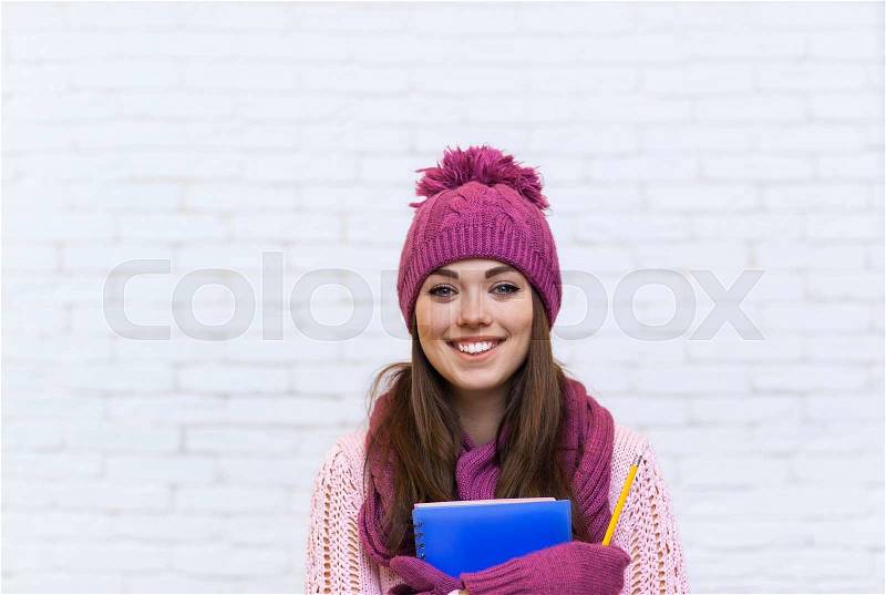 Attractive Student Smile Teenage Girl In Pink Hat Holding Folder Pencil Over White Brick Background, stock photo