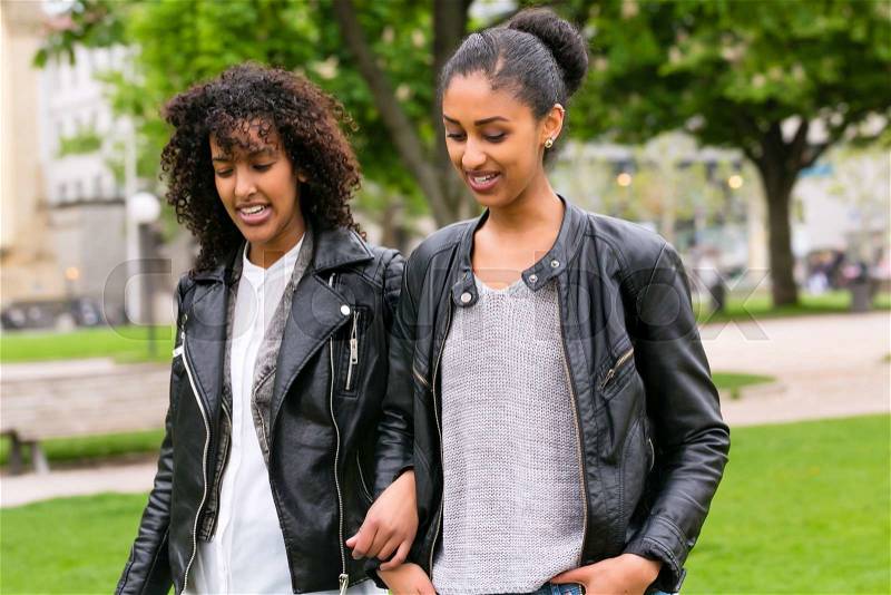 Two north African teen friends take a walk in the park talking , stock photo