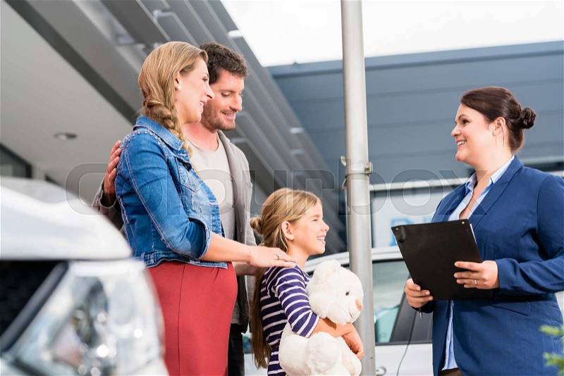 Car dealer advising family on buying auto showing price list, stock photo
