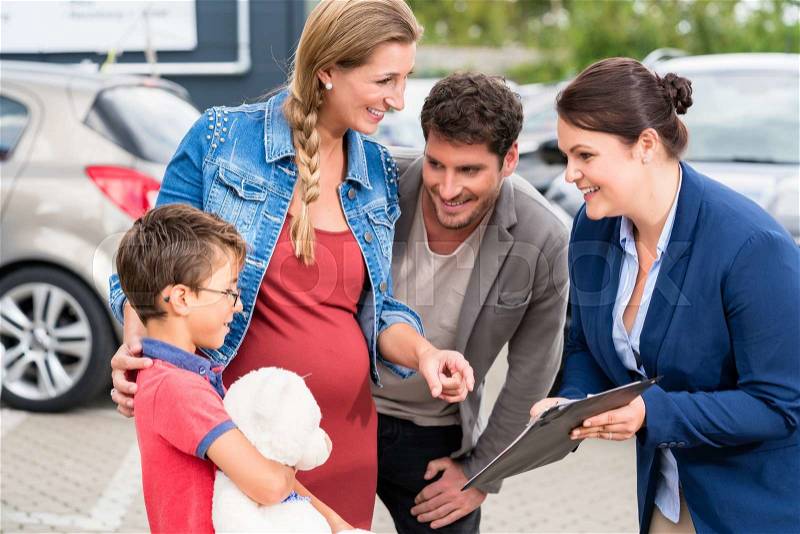 Car dealer advising family on buying auto showing price list, stock photo