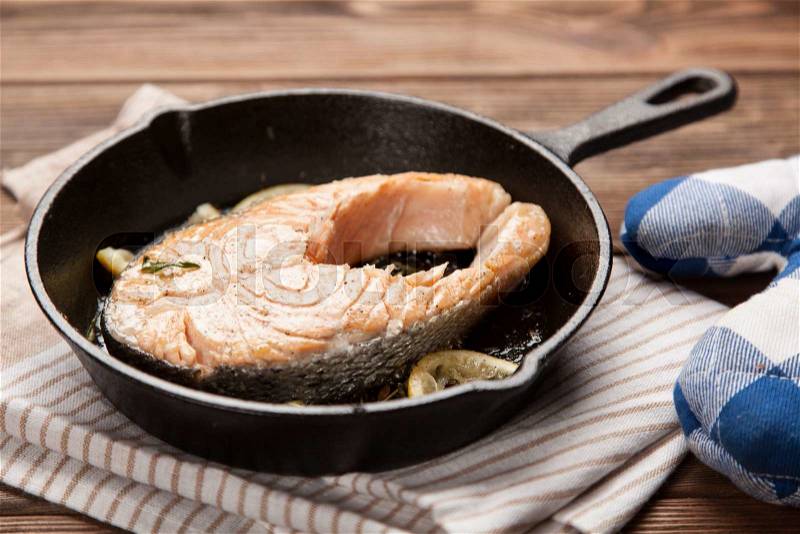 Salmon fried in a cast iron pan, stock photo