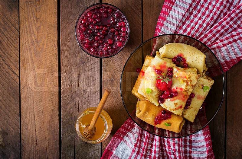 Golden pancakes with cranberry jam and honey in a rustic style. Top view, stock photo