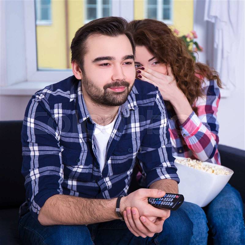 Young couple watching scary movie on tv at home, stock photo