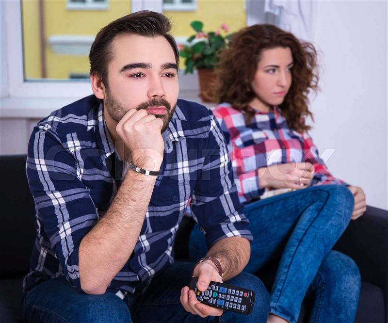 Woman being bored watching tv with her boyfriend, stock photo