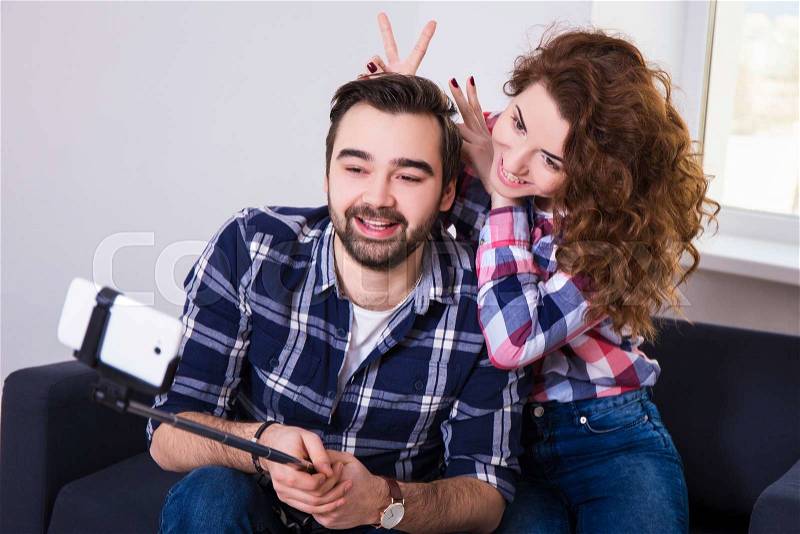 Happy funny couple taking photo with cell phone on selfie stick, stock photo