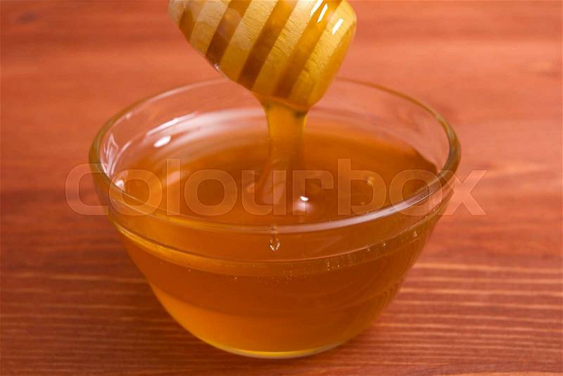 Wooden honey stick to extract honey from the container, stock photo