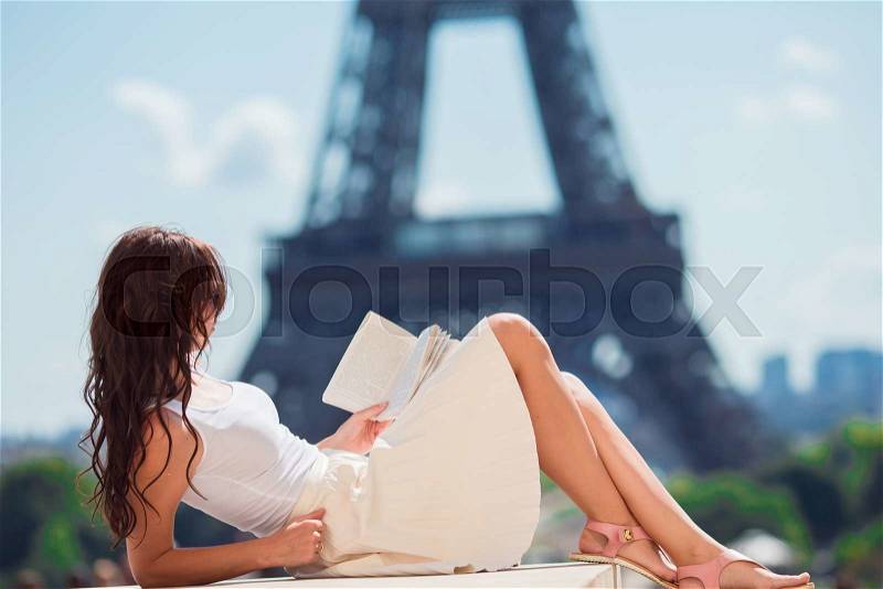 Beautiful woman reading book in Paris background the Eiffel tower, stock photo
