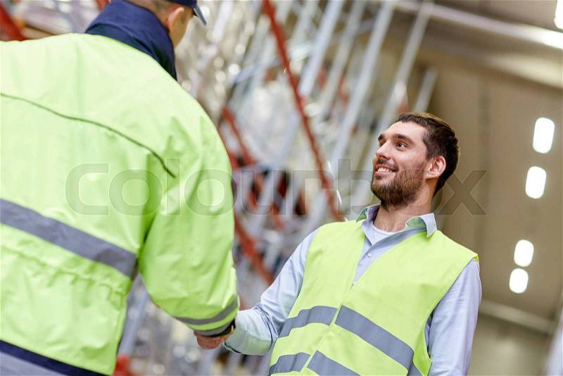 Wholesale, logistic, people, agreement and export concept - manual worker and businessmen in reflective safety vests shaking hands and making deal at warehouse, stock photo