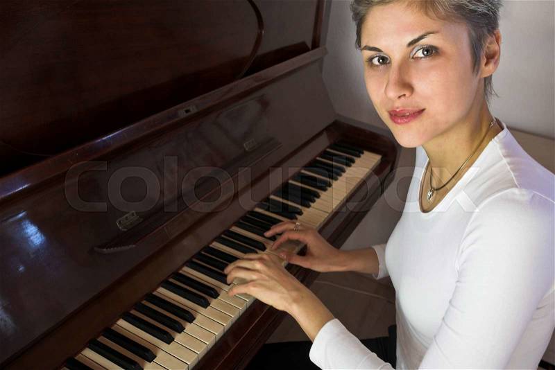 Blond short hair woman woman with white Tshirt playing piano, stock photo