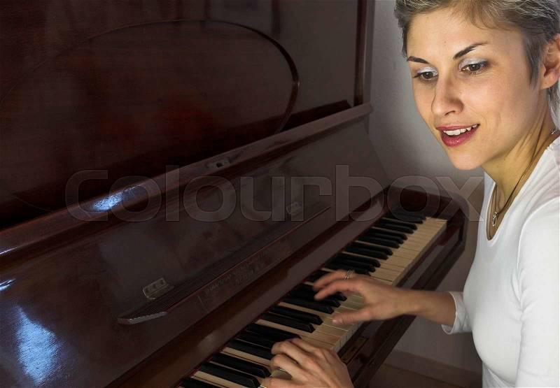Blond short hair woman woman with white Tshirt playing piano, stock photo