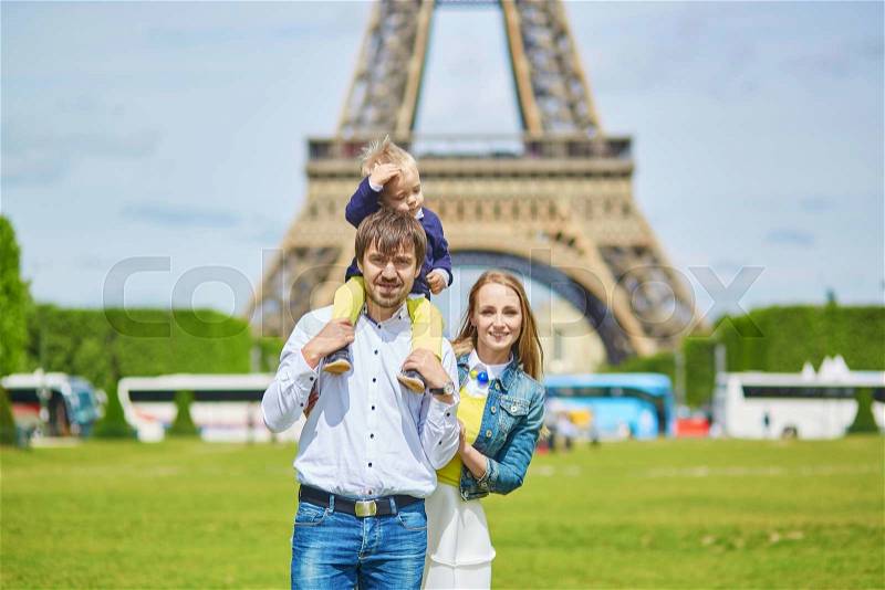 Happy family of three, mother, father and little toddler boy, having picnic in Paris near the Eiffel tower, stock photo