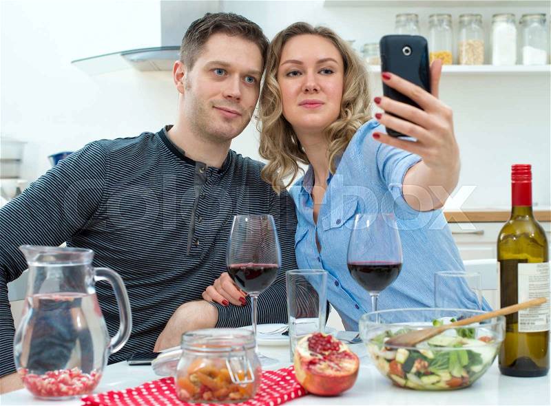 Young couple having dinner at home. Taking selfie with mobile phone, stock photo