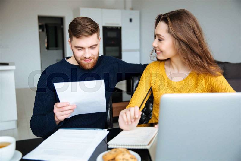 Happy young couple calculating bills at home, stock photo