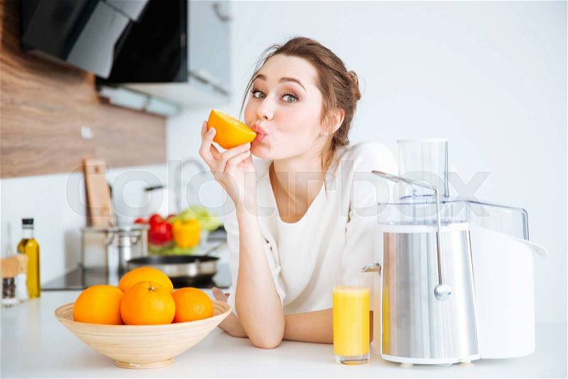 Cute charming young woman making juice and eating oranges on the kitchen, stock photo
