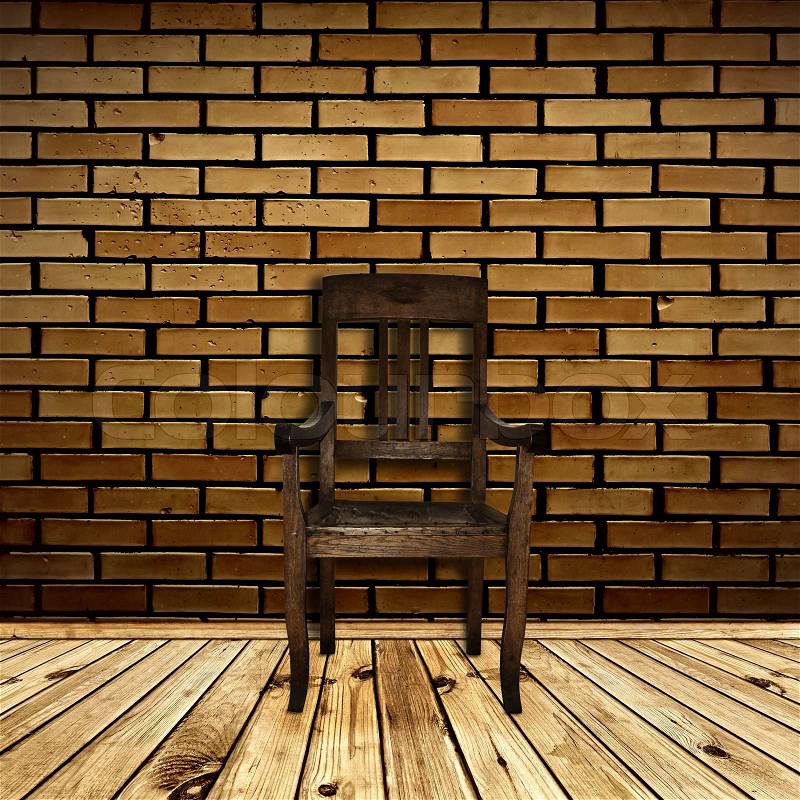 Single chair at wooden floor against beige brick wall, stock photo
