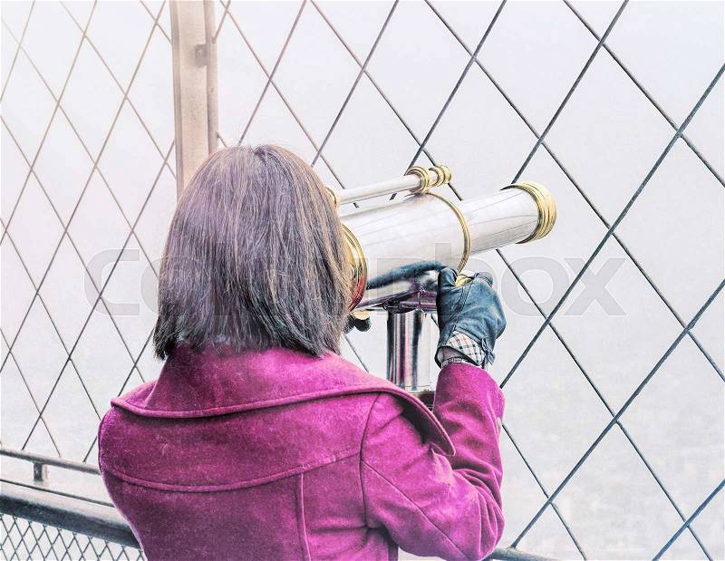 Vintage back view of a woman looking in city telescope, stock photo