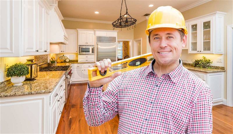 Smiling Contractor with Level Wearing Hard Hat Standing In Custom Kitchen, stock photo