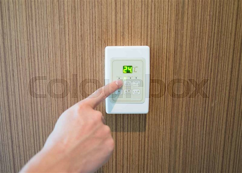 Hand turning on and off air-condition panel mounted on wall, stock photo