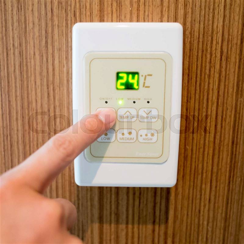 Hand turning on and off air-condition panel mounted on wall, stock photo