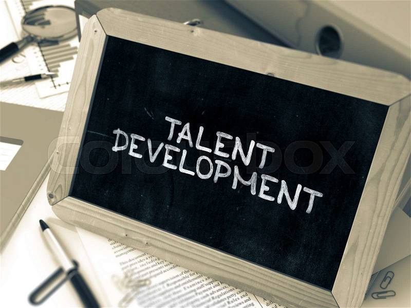 Talent Development Handwritten on Chalkboard. Composition with Small Chalkboard on Background of Working Table with Ring Binders, Office Supplies, Reports. Blurred Background. Toned Image, stock photo
