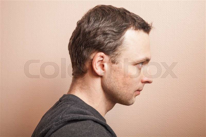 Young serious Caucasian man profile studio portrait over gray wall background, stock photo