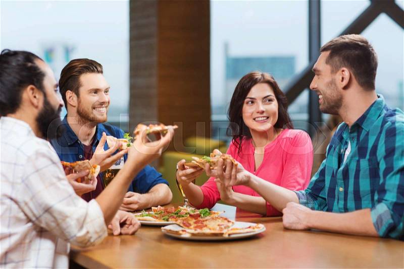 Leisure, food and drinks, people and holidays concept - smiling friends eating pizza and drinking beer at restaurant or pub, stock photo