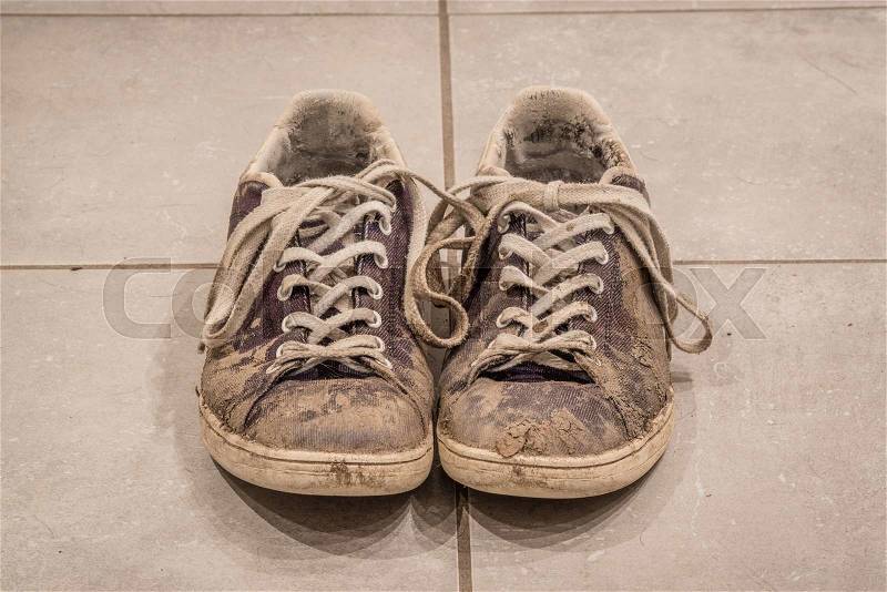 Pair of dirty shoes with mud on the floor, stock photo