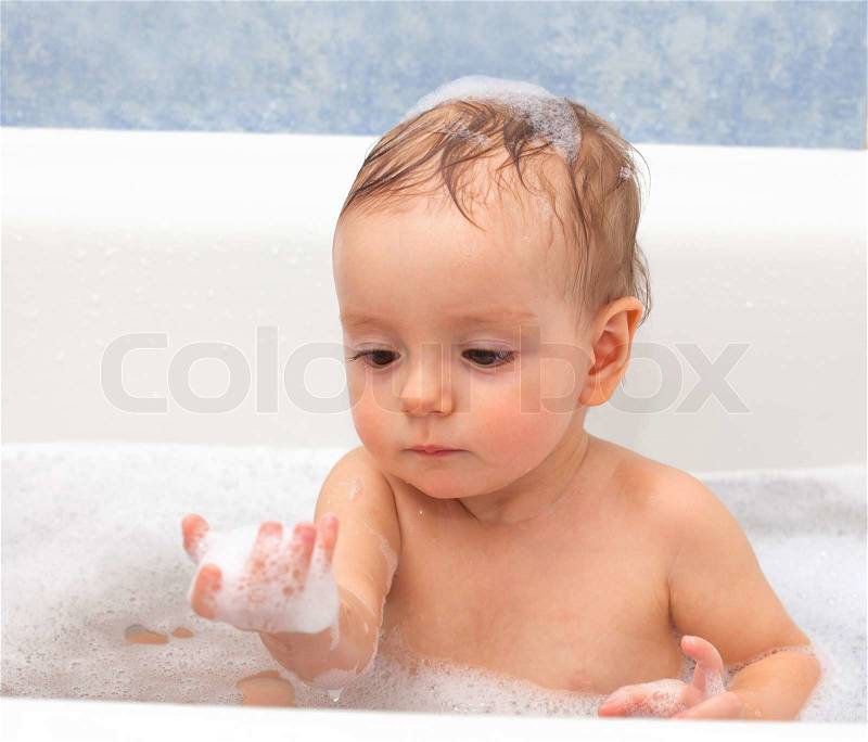 Adorable one-year old baby playing with foam in the bathroom, stock photo