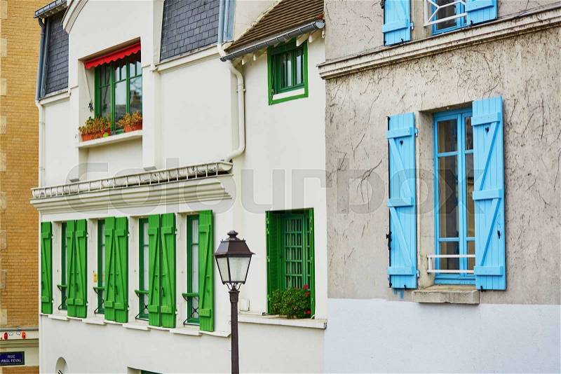 Beautiful Parisian buildings with green and blue window shutters and streetlamp, stock photo