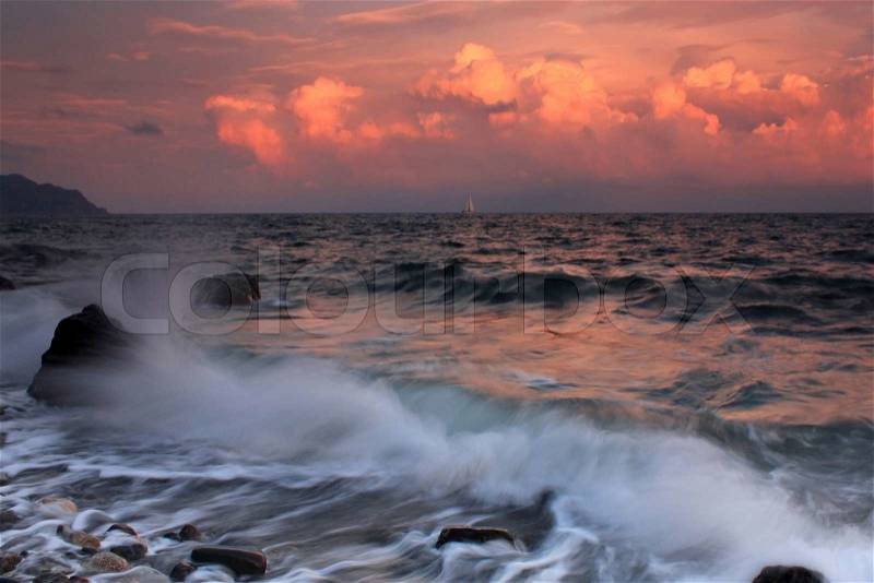 Storm waves crash on a rock in the sunset on the ocean coast, stock photo