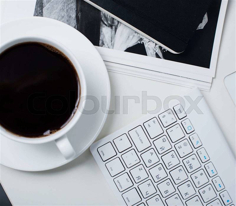 Modern office interior closeup, cup of coffee and computer keyboard. Business objects on white working table background, stock photo