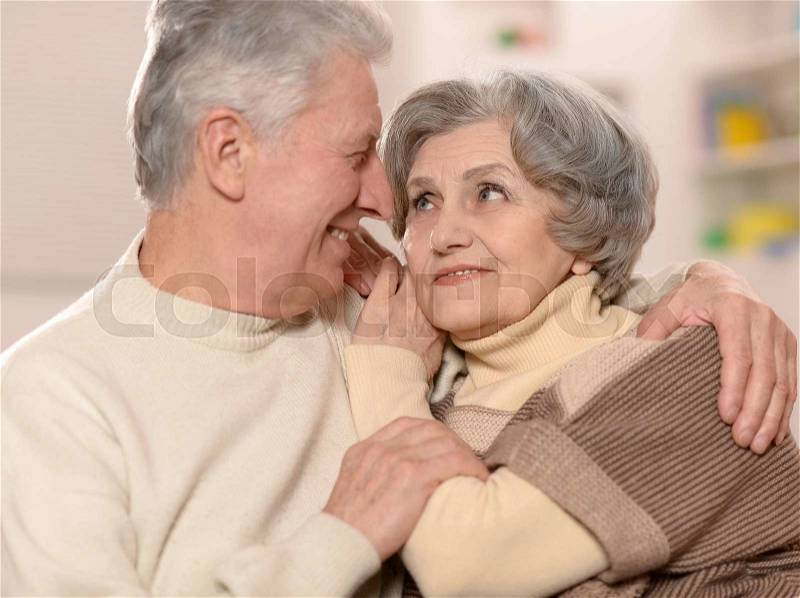 Two elderly people sitting at home on couch, stock photo