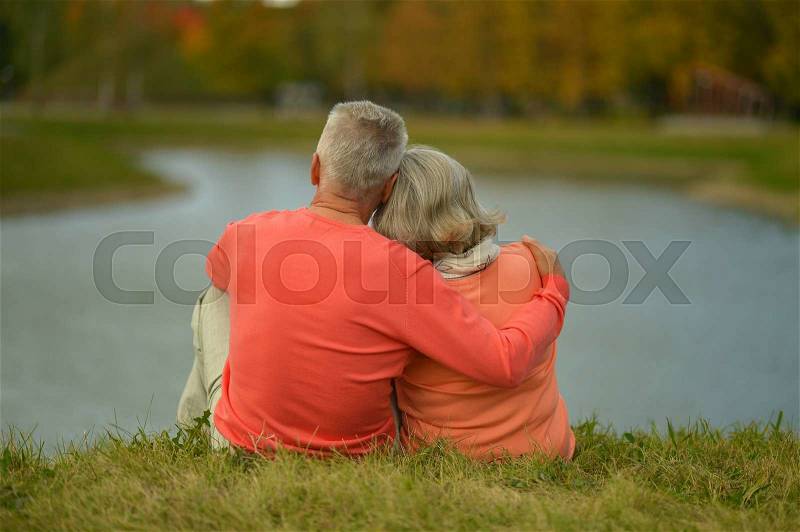 Happy senior couple near lake during sunset at autumn, stock photo