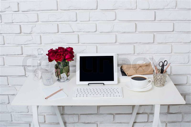Young business woman workspace, white feminine office interior closeup, roses flowers, cup of coffee and laptop on a table, stock photo