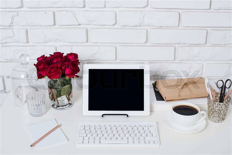 Young business woman workspace, white feminine office interior closeup, roses flowers, cup of coffee and laptop on a table, stock photo