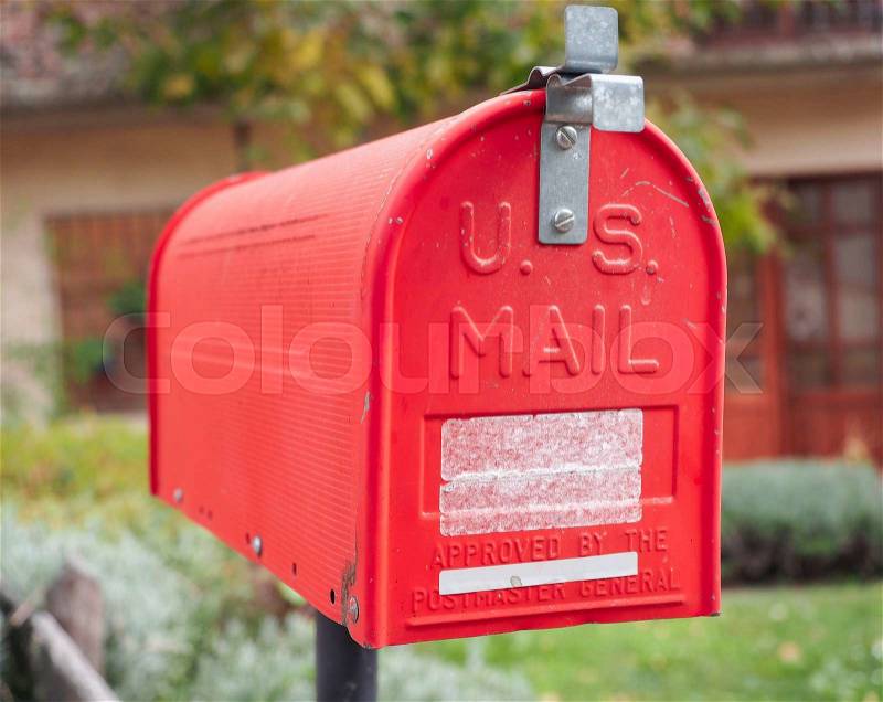 An old home letter box, red painted, with background of rural house, stock photo
