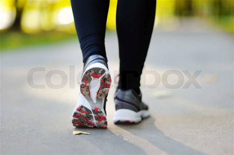 Runner feet running on road closeup on shoe. Woman fitness jog workout, wellness concept, stock photo