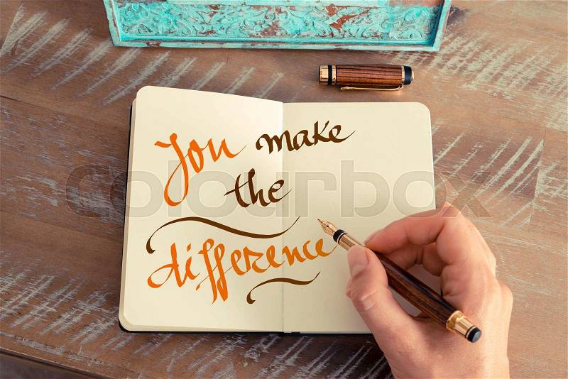 Retro effect and toned image of a woman hand writing a note with a fountain pen on a notebook. Handwritten text YOU MAKE THE DIFFERENCE, motivation concept, stock photo